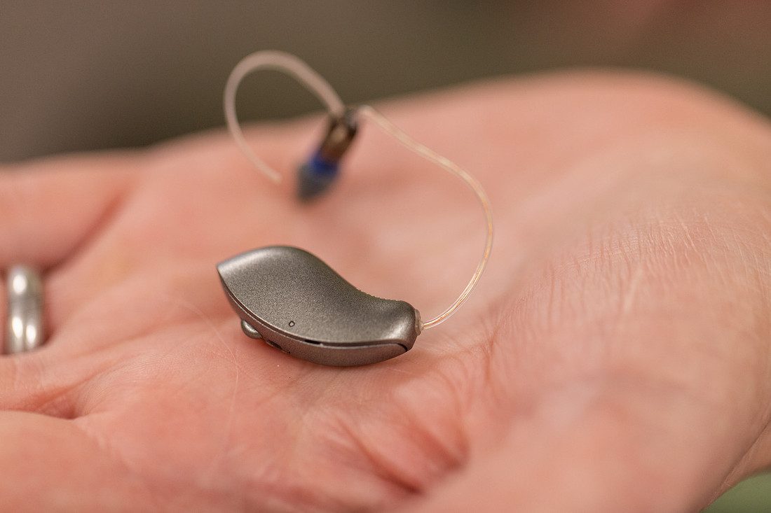 Small receiver-in-canal hearing aid held in the palm