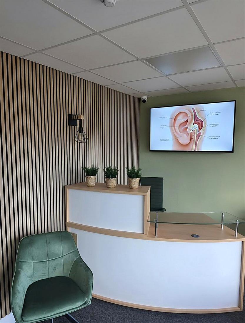 Inside the BFG Hearing Solutions clinic at Team Valley, Gateshead — modern reception with an ear-anatomy display on screen